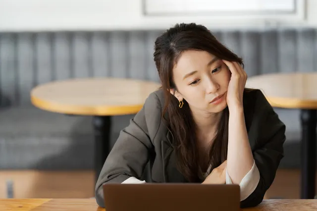 パソコンの前で悩む女性