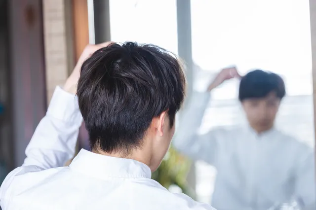 鏡で身だしなみを整える男性