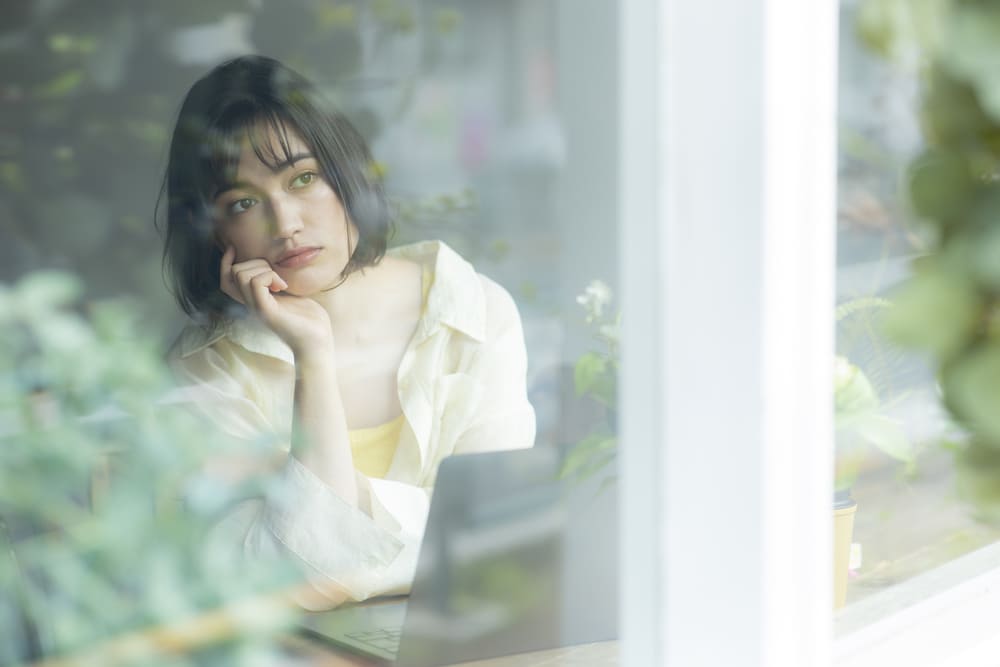 窓辺で物憂げな女性