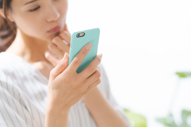 スマホを見て悩む女性