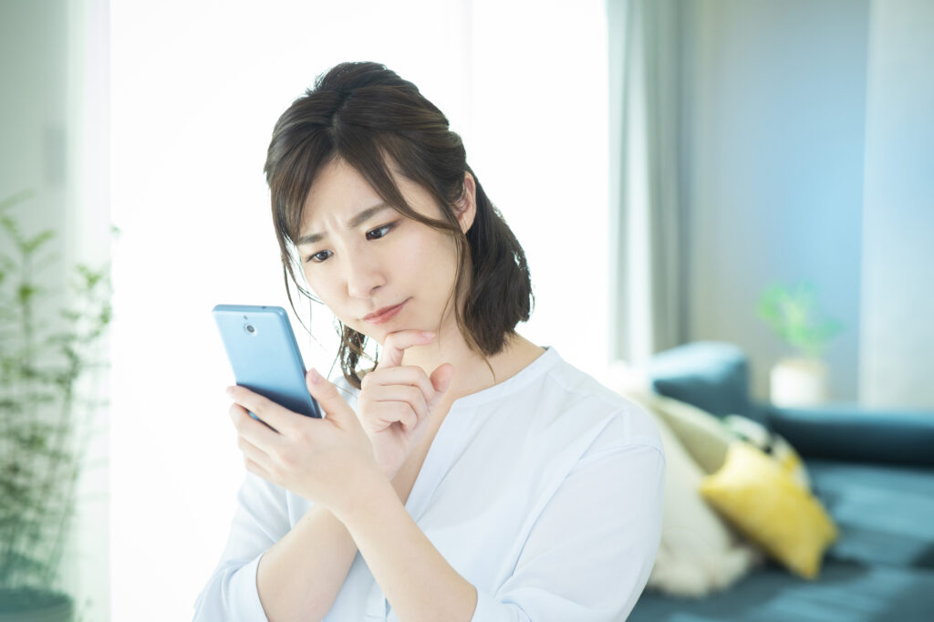 スマホを見ながら悩む女性