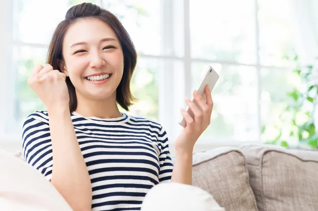 スマホを持ってガッツポーズをする女性
