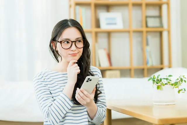 スマホを見ながら考える女性
