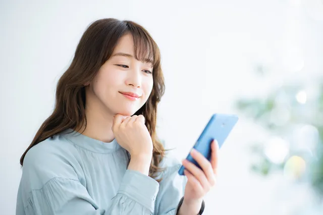 スマホを見ながら考える女性