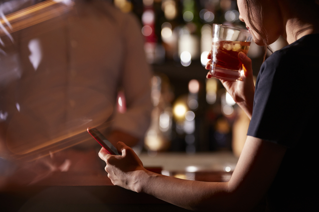 Barでスマホを見る女性