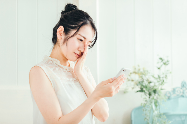 スマホを見て悩む女性