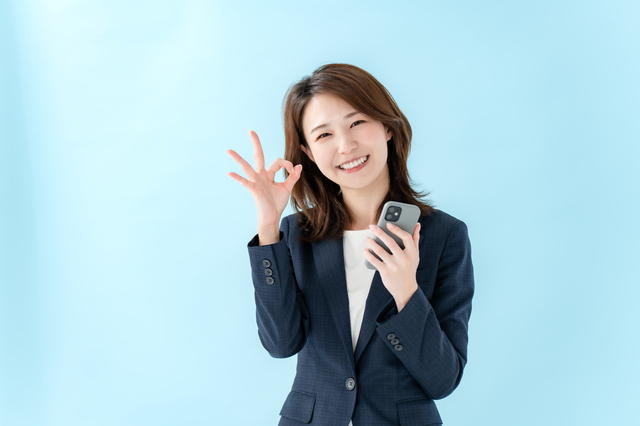 スマホを持ってOKサインを出す女性