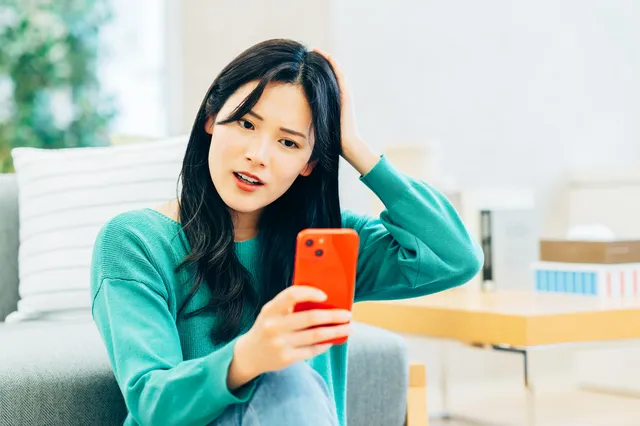 スマホを見て悩む女性