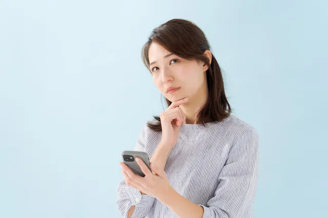 スマホを持って悩む女性