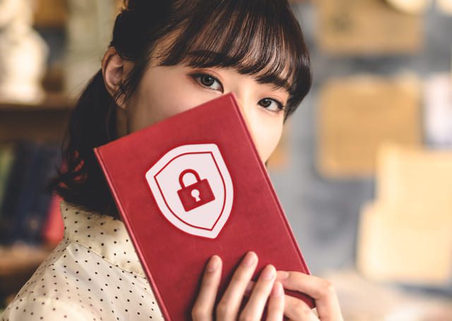 セキュリティマークの付いた本で顔を隠す女性