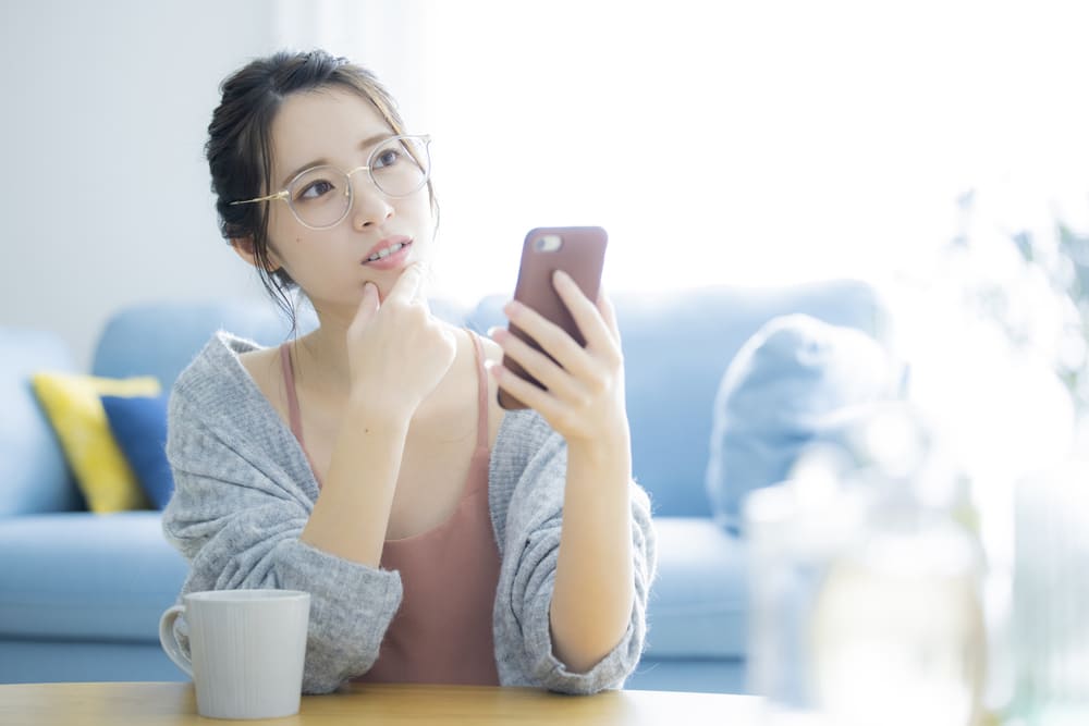 スマホを持って考える女性