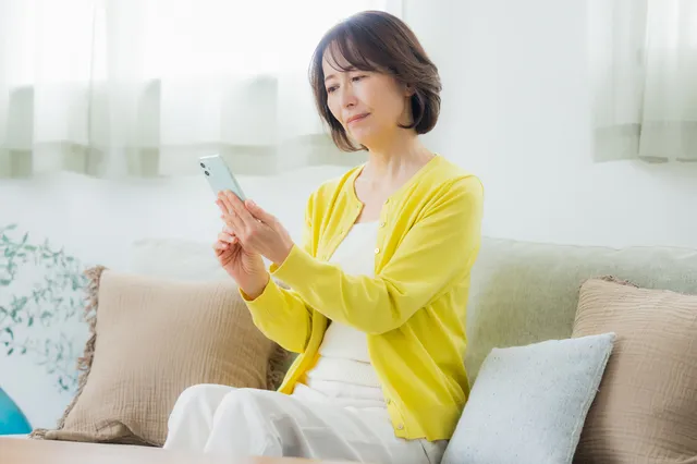 スマホを持って考えるシニア女性