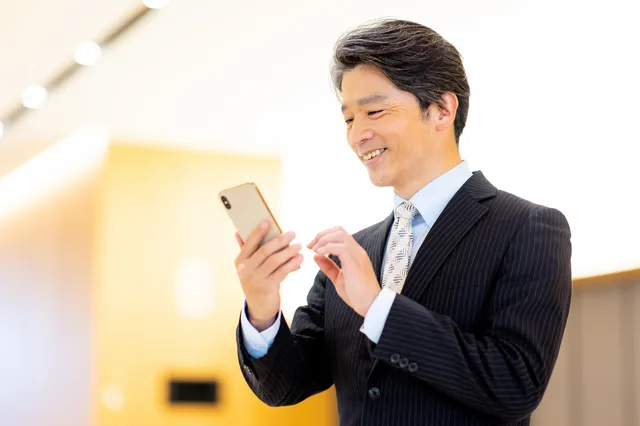 スマホを操作するスーツを着たシニア男性