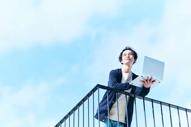 パソコンを持って屋上に佇む男性