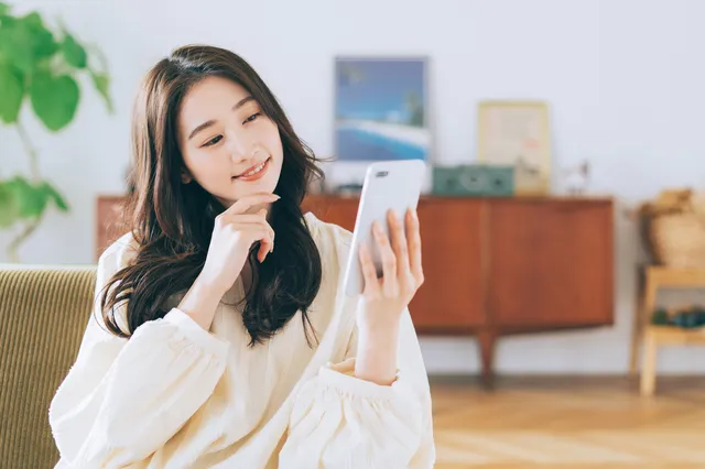 スマホを眺めて考える女性