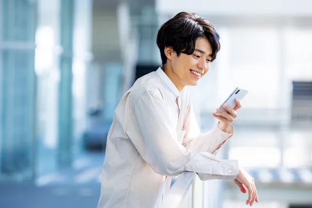 笑顔でスマホを見る20代男性